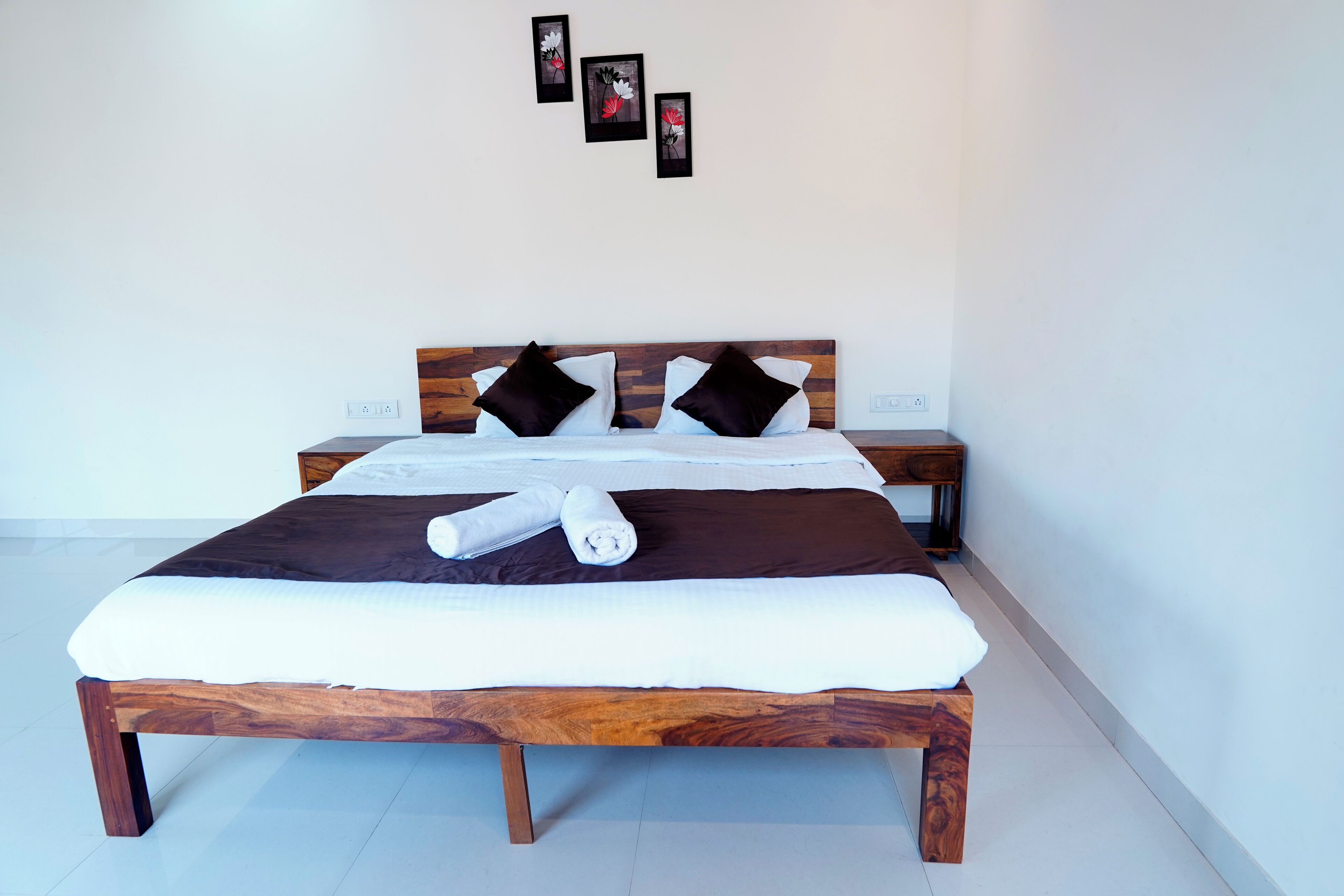 A neatly made bed with a wooden headboard, white bedding, and two pillows.