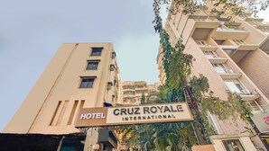 Señal de hotel para 'Cruz Royale International' con un edificio moderno al fondo.