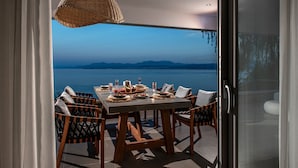 Un espace de restauration en plein air avec une table dressée pour deux personnes, offrant une vue sur un plan d’eau et des montagnes.