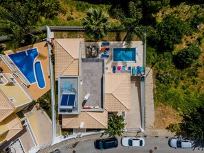 Vue aérienne d’un complexe hôtelier doté de plusieurs piscines, d’un patio couvert et d’un parking.