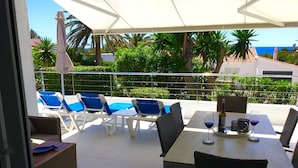 Una terrassa amb taula, cadires i vista al mar.