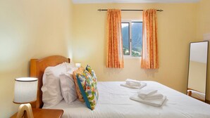 Une chambre d’hôtel avec un lit, une table de chevet avec une lampe, une fenêtre avec des rideaux et une vue sur l’extérieur.