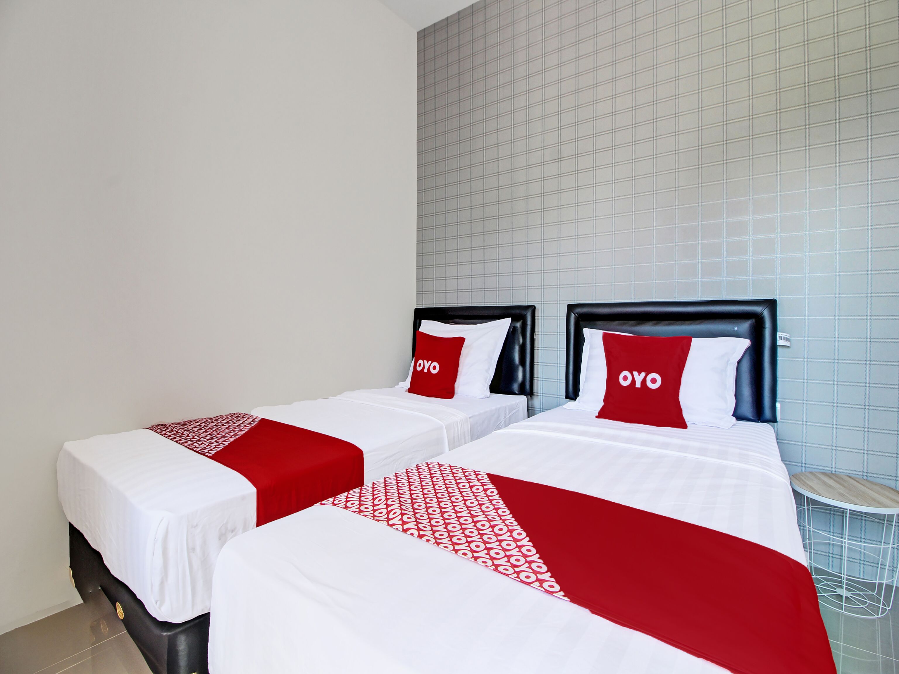 A hotel room with two beds, each with a black headboard and red and white bedding.