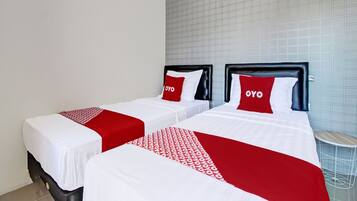 A hotel room with two beds, each with a black headboard and red and white bedding.
