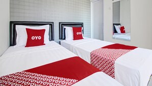 Habitación de hotel con dos camas, cada una con cubrecama y almohadas rojas y blancas, y un espejo grande en la pared.