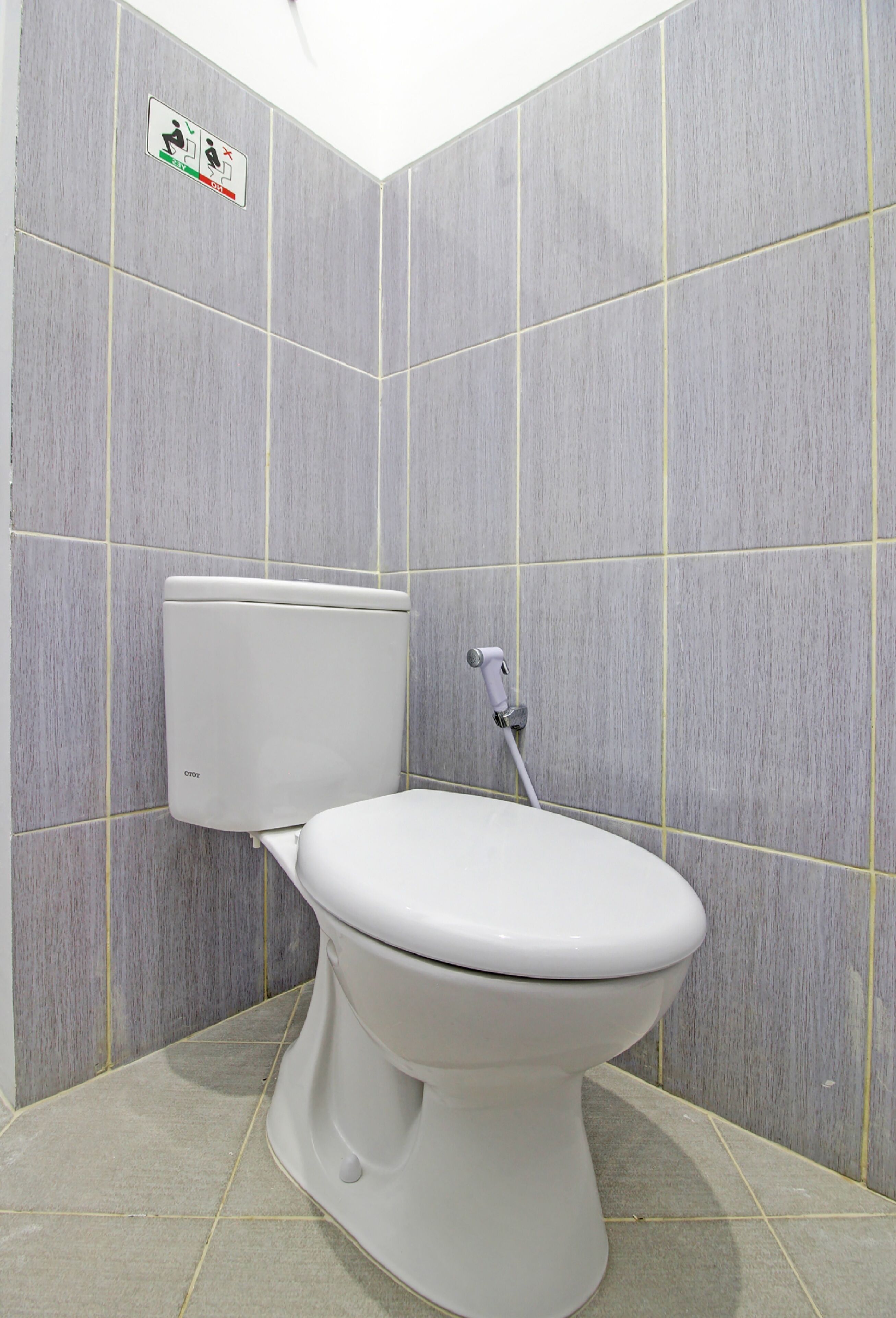 A bathroom with a toilet, tiled walls, and a floor.