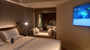 A hotel room with a bed, a sofa, a TV screen displaying 'Welcome to Samsung Hotel', and a painting on the wall. - Capital O 950 Acqua Novotel Tower (Mandaluyong)