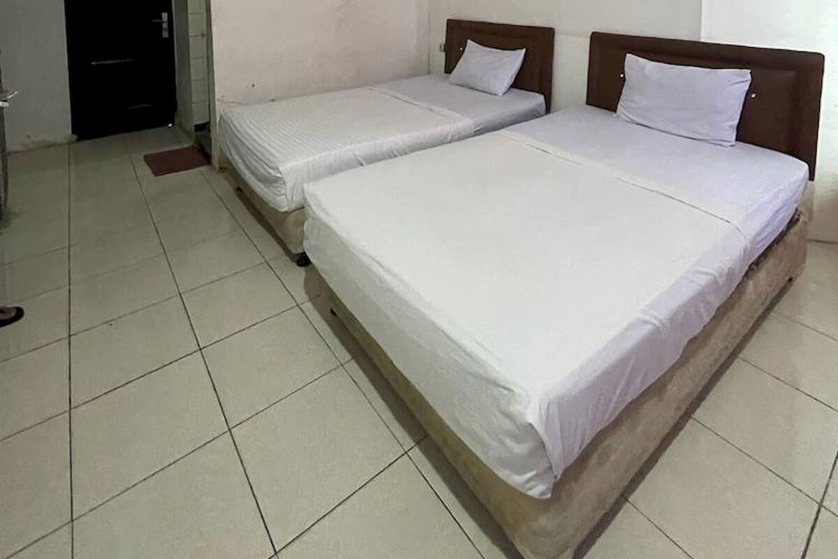 Een kamer met twee eenpersoonsbedden, een deur en een airconditioning.