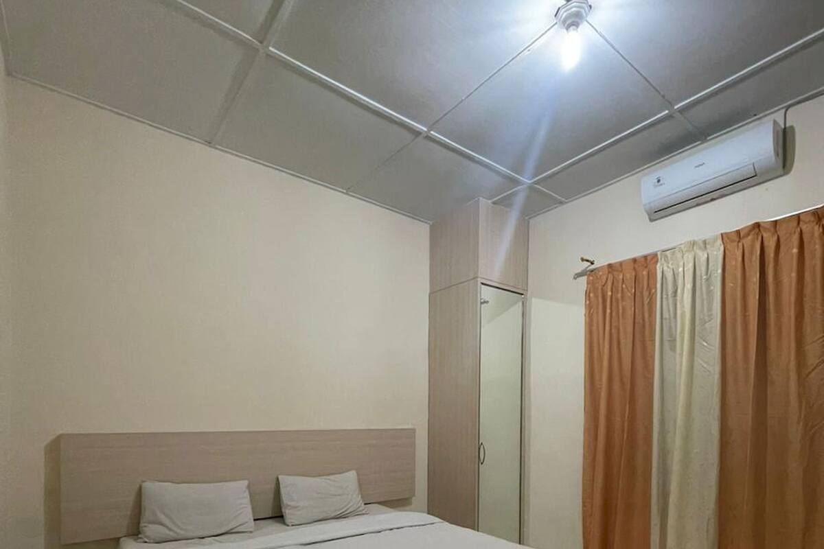 Een slaapkamer met een bed, een kledingkast, een spiegel en een airconditioning.