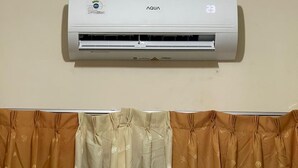 Een luchtverkoeler aan de wand, met bedieningspaneel en temperatuurweergave.