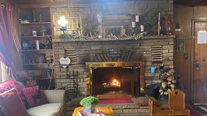 A cozy living room with a fireplace, a sofa, a coffee table, and a bookshelf.