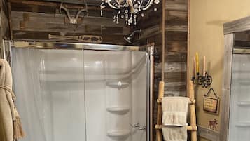 A rustic cabin bathroom with a shower, toilet, and wooden vanity.