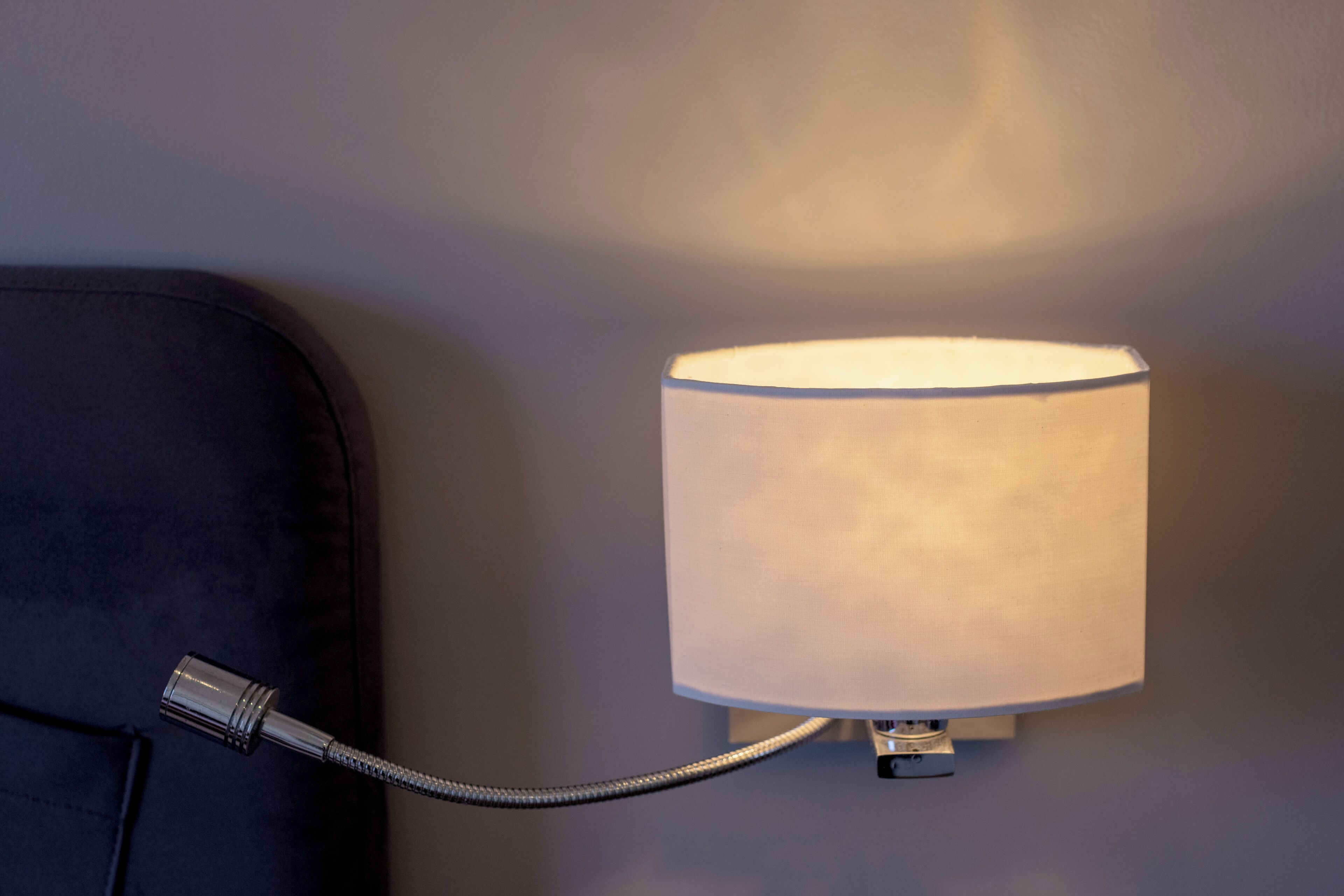 A wall-mounted lamp with a flexible neck, attached to a wall.