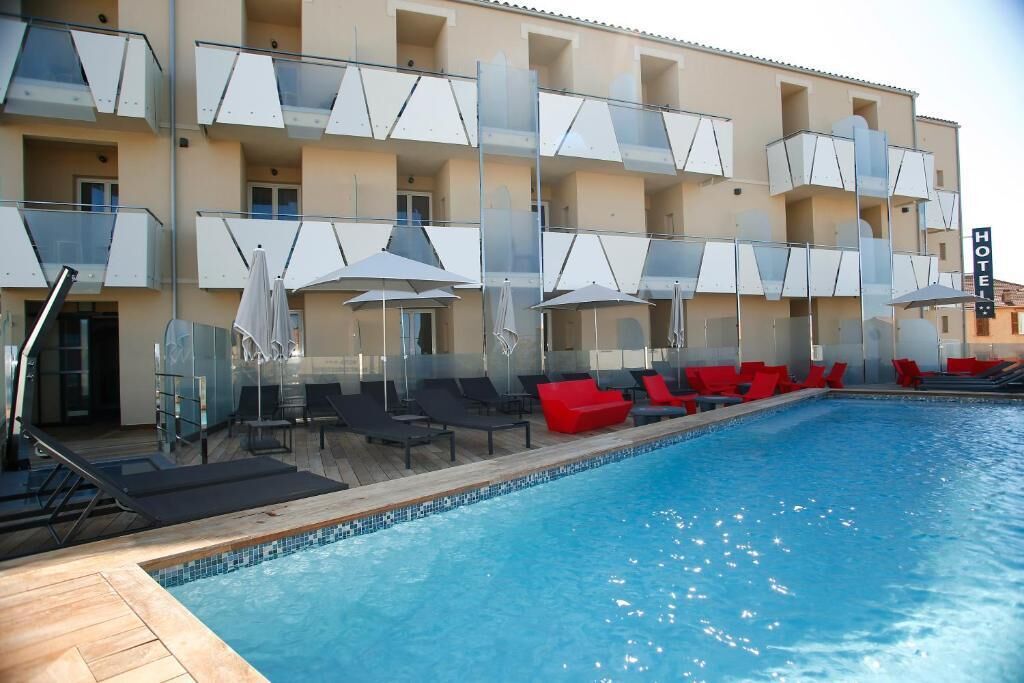 Un hotel con piscina, mobiliario exterior y un balcón con vistas.