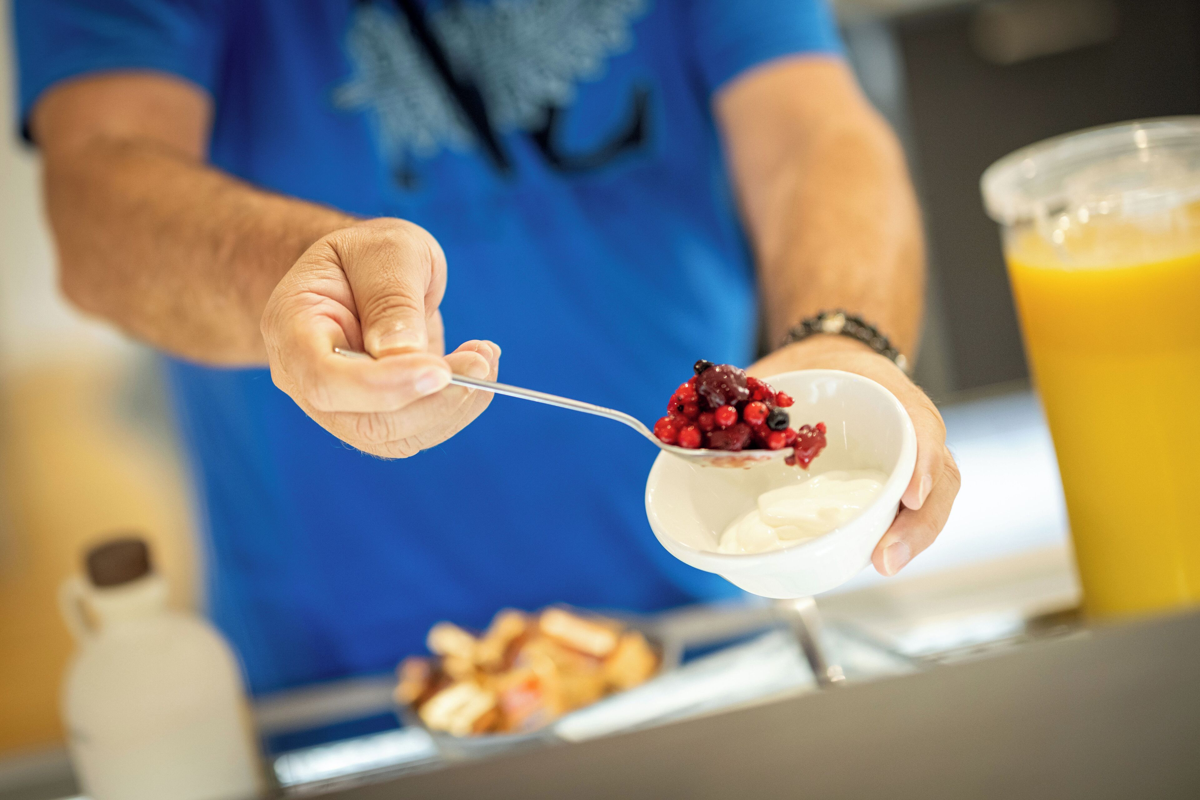 Eine Person hält einen Löffel mit einer Schüssel Joghurt und Beeren.
