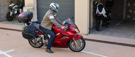 Une personne conduisant une moto rouge avec une sacoche noire.