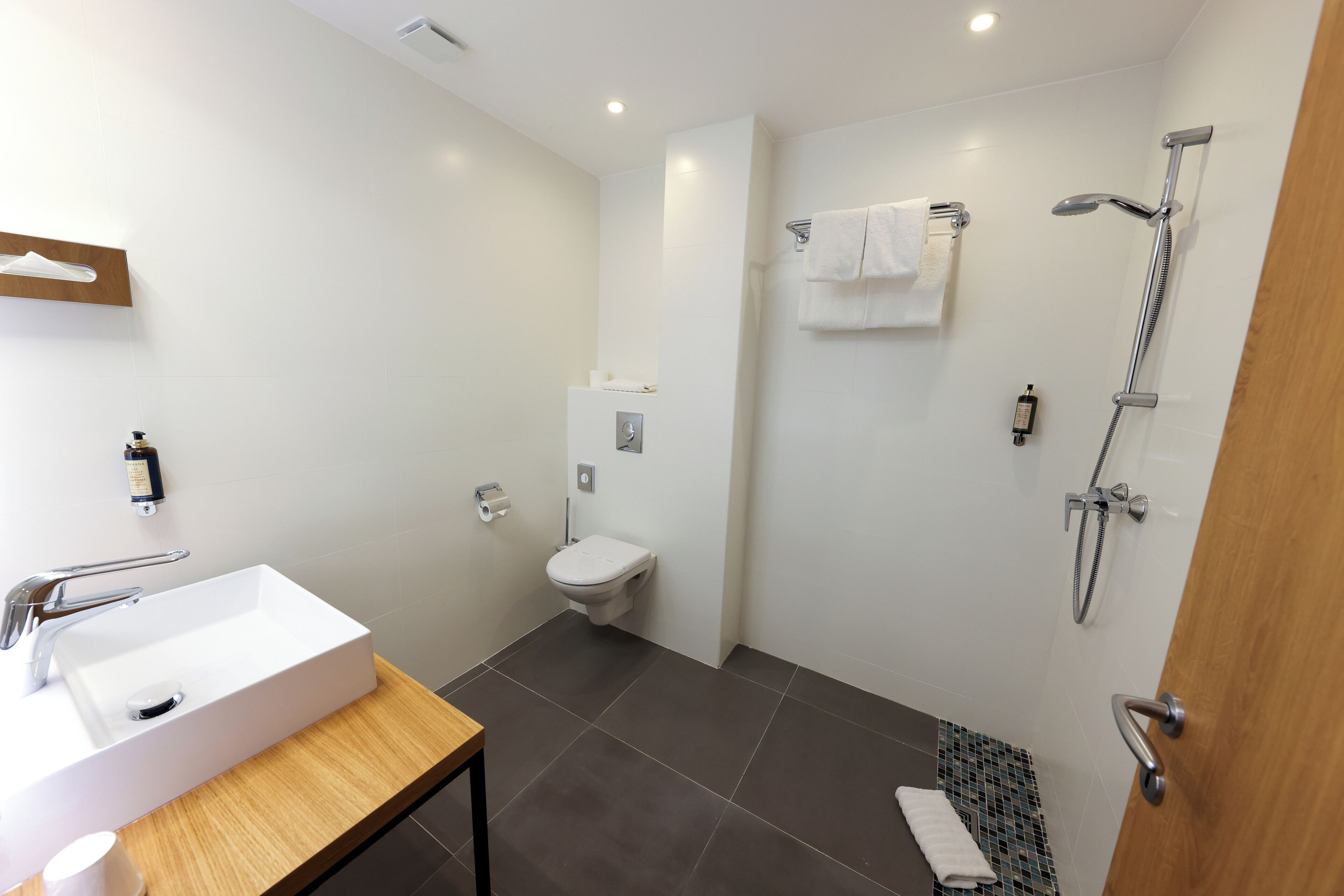 A modern bathroom with a white sink, toilet, and shower.