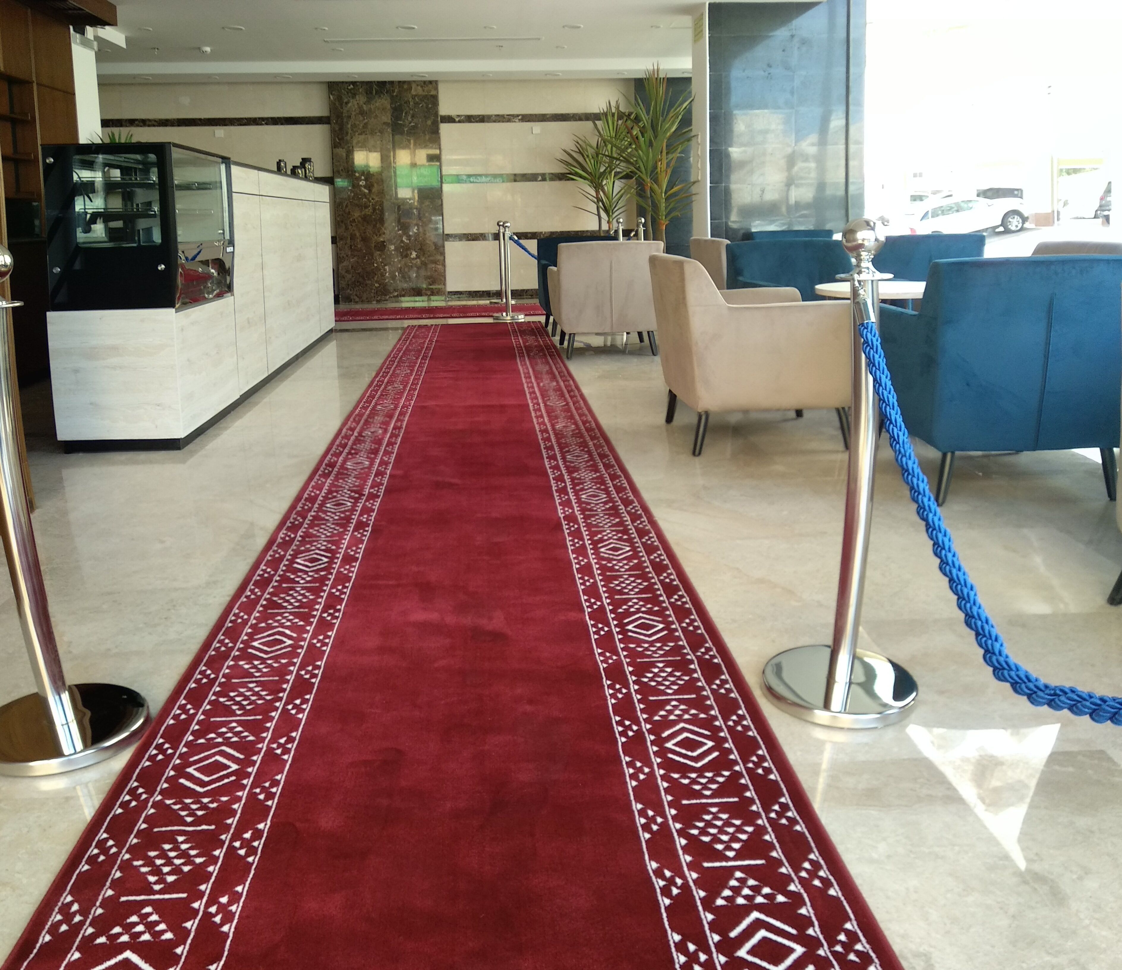 A hotel lobby with a red carpet, seating area, and a reception desk.
