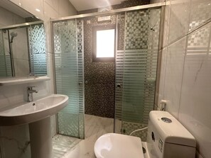 Une salle de bain avec une douche à parois de verre, un lavabo et des toilettes.