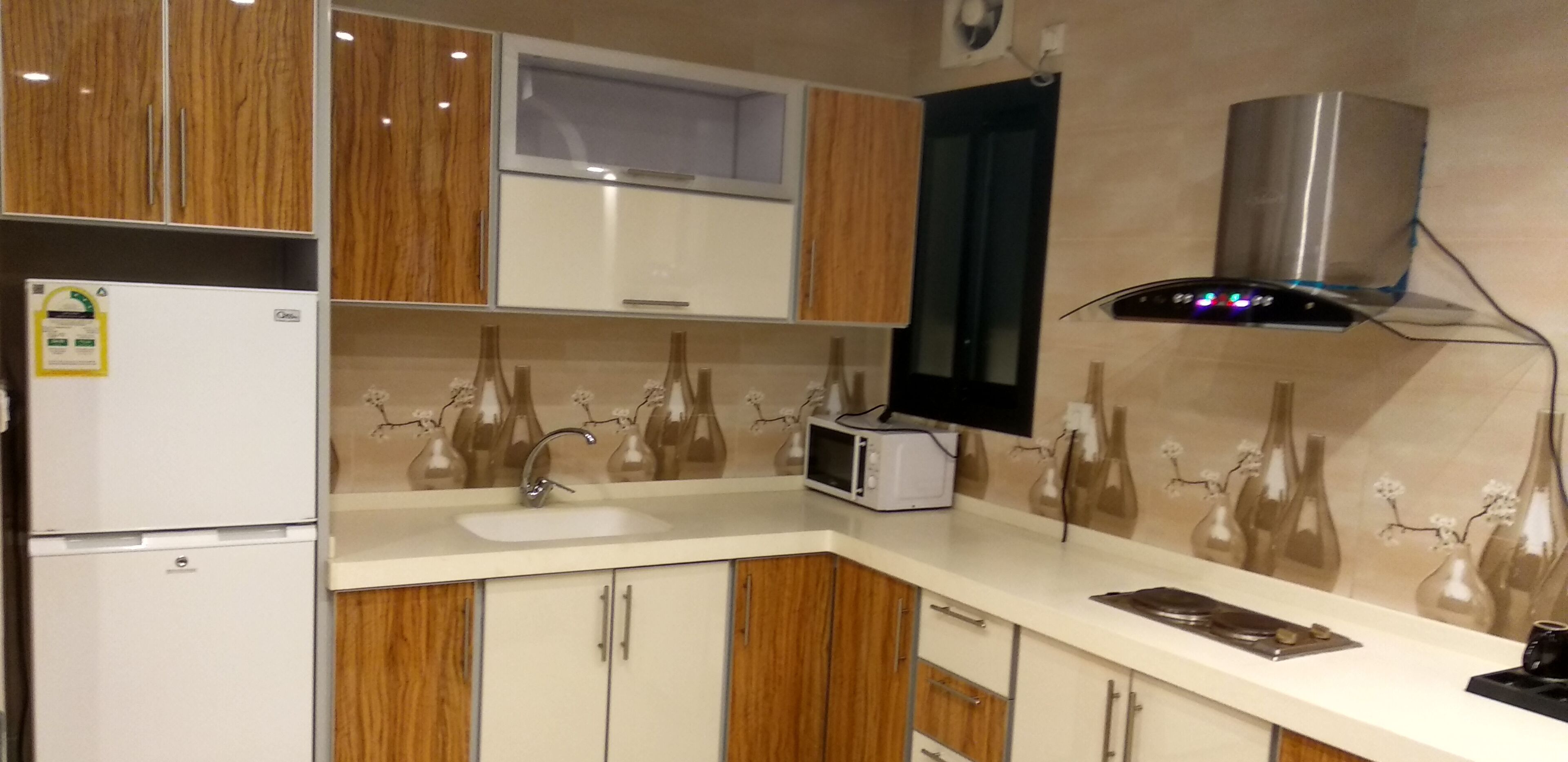 A modern kitchen with wooden cabinets, a built-in microwave, a sink, and a decorative backsplash.