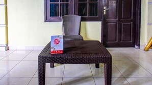 A wicker table with a sign in front of a window and a door. - Hotel O Kos Agi Mataram Near Masjid Hissoh Al-Faham (Mataram)