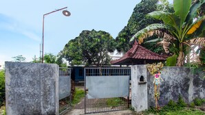 A gated entrance with a metal gate, a concrete wall, and a small structure with a tiled roof. - Hotel O Kos Agi Mataram Near Masjid Hissoh Al-Faham (Mataram)