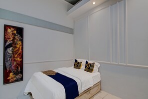 A bedroom with a bed, white walls, a ceiling light, and a large painting on the wall. - SPOT ON 92449 Libersa Homestay Syariah (Pekanbaru)