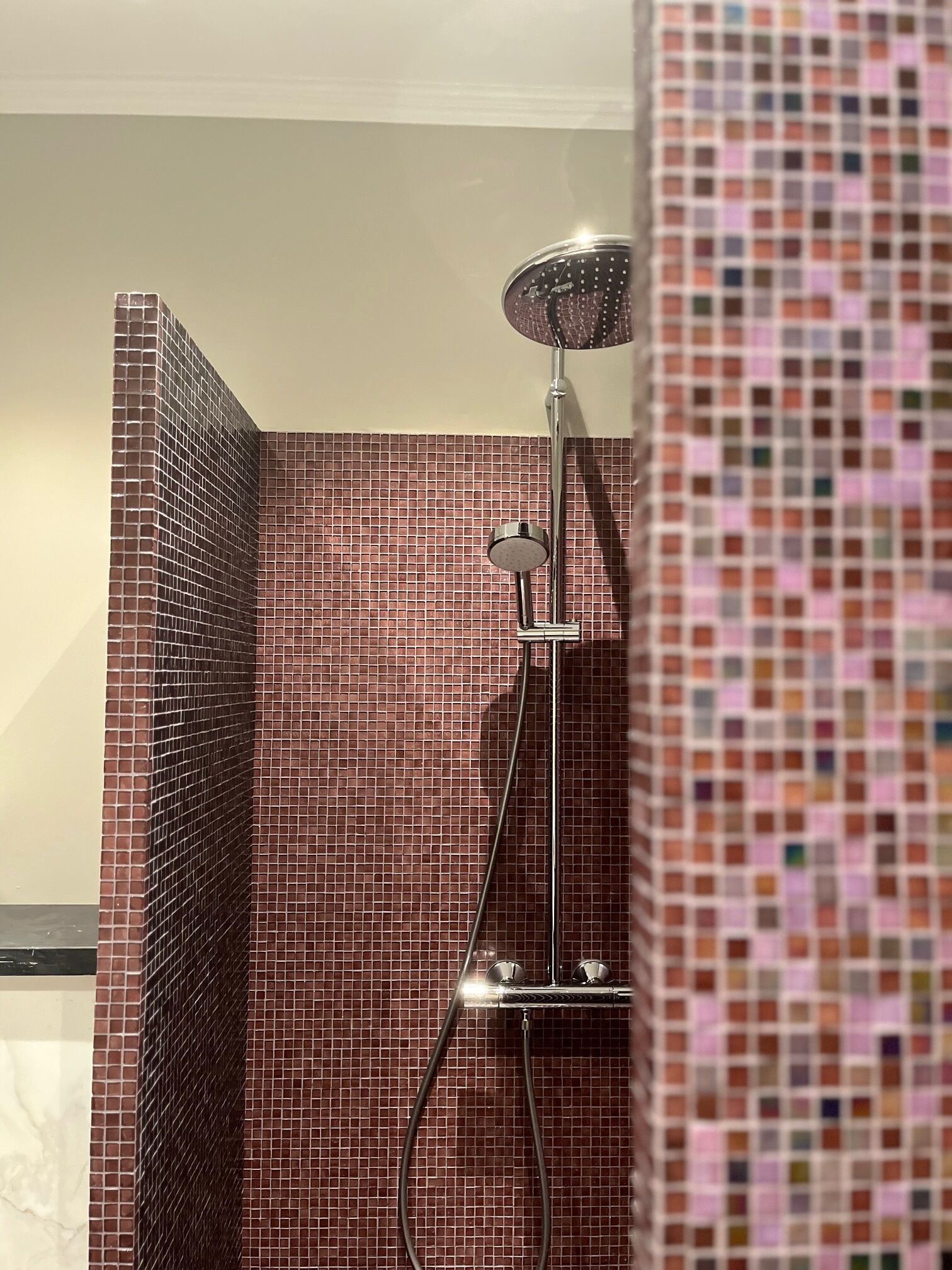 A shower area with a tiled wall and a showerhead.