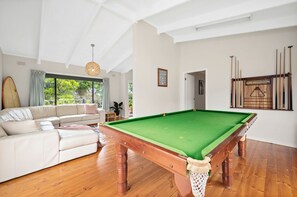 A spacious living room with a pool table, a sofa, and a surfboard. - Three Beaches (Anglesea)