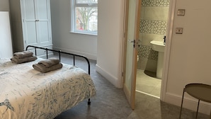 A bedroom with a bed, a wardrobe, a bathroom with a shower, and a small table. - Beautiful Townhouse in Stratford Upon Avon (Stratford-upon-Avon)