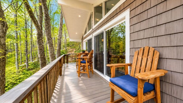 A wooden deck with a table and chairs, overlooking a forest. - Treetop & Waterfront! Quiet Cove, Hot Tub, Kayaks, Game Room and more (Moneta)