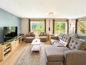 A living room with a TV, sofas, a coffee table, and a ping pong table.