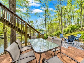 A deck with a glass table and chairs, overlooking a body of water and surrounded by trees. - Treetop & Waterfront! Quiet Cove, Hot Tub, Kayaks, Game Room and more (Moneta)