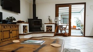 Un salon doté d’une cheminée, de meubles en bois, d’un téléviseur et offrant une vue sur l’extérieur.