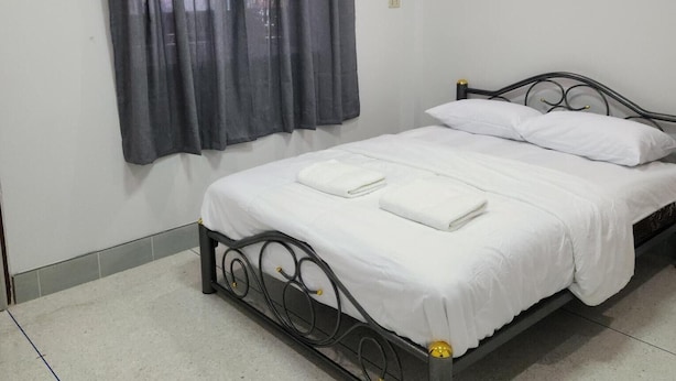 A single bed with a metal frame, white bedding, and a grey curtain. - Jipu Homestay (Betong)