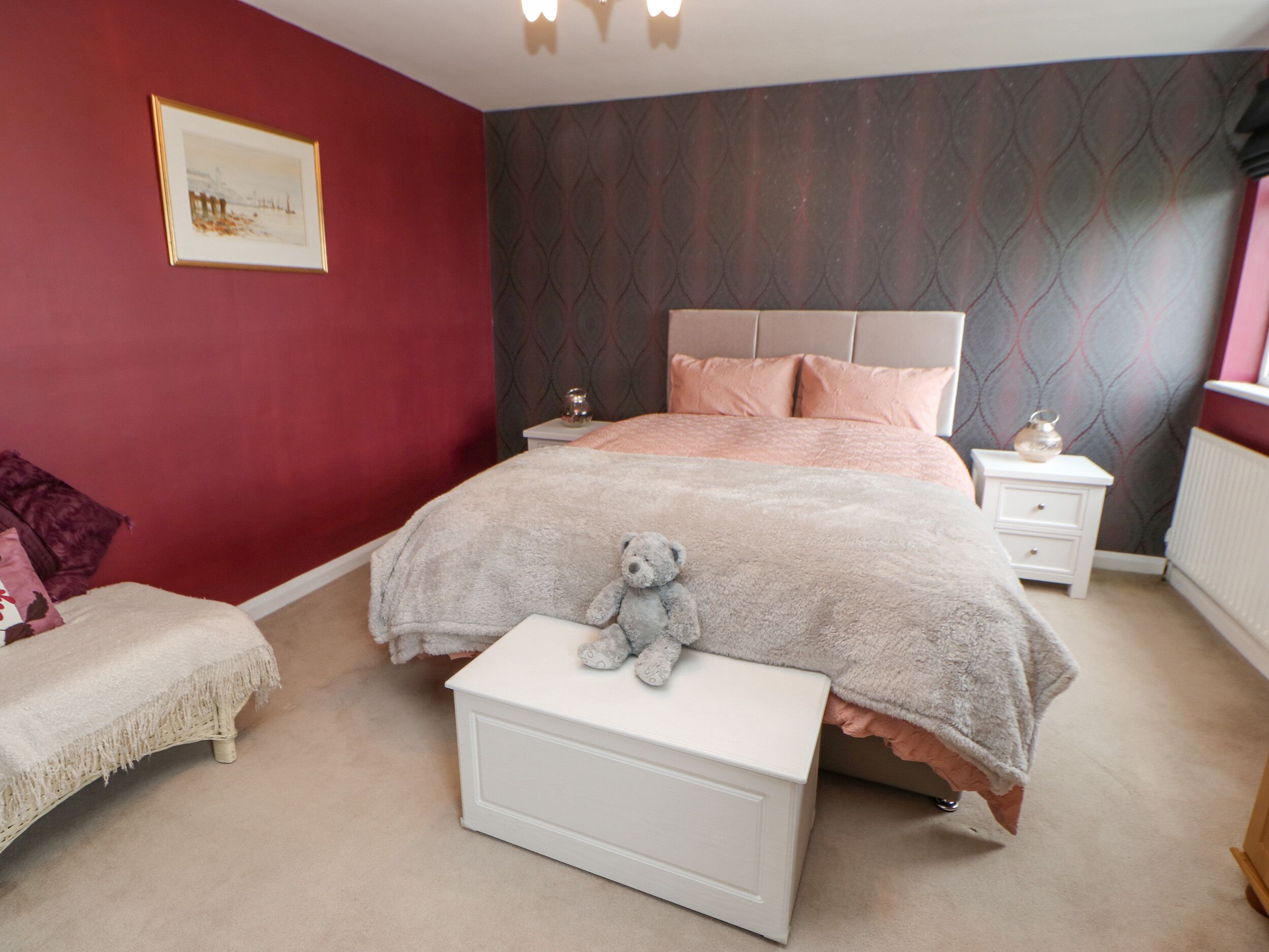 A bedroom with a bed, nightstands, a dresser, a teddy bear, and a framed picture on the wall.