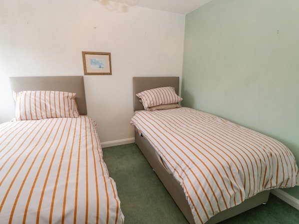 A room with two single beds, each with striped bedding and headboards.