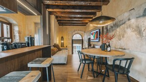 A modern kitchen with a wooden bar, a dining area with a round table and chairs, and a cozy seating area with a sofa. - Oniros Residenza Vecchia  (Chania)