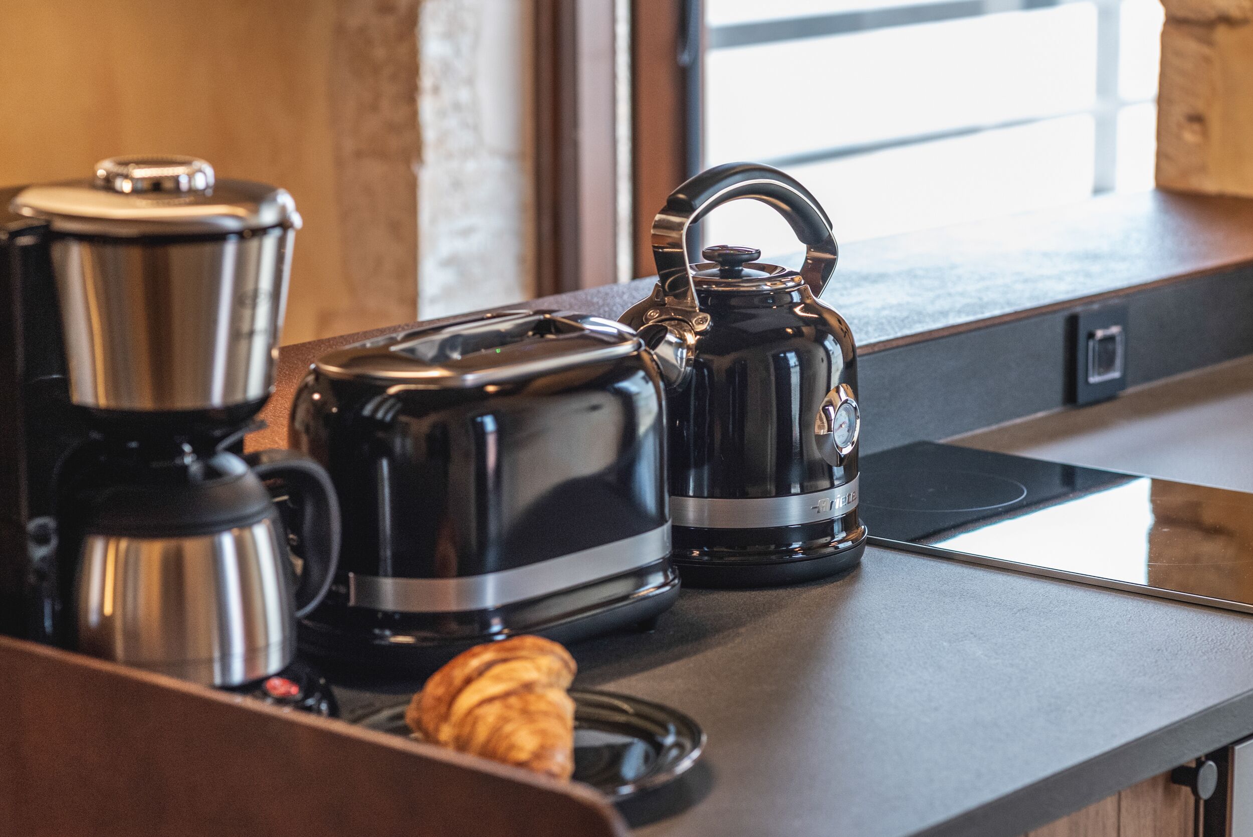 A kitchen counter with a coffee maker, a kettle, and a toaster.