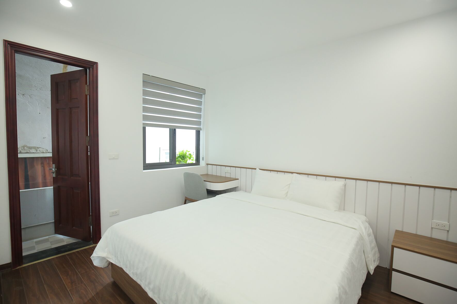 A bedroom with a bed, a desk, and a chair.
