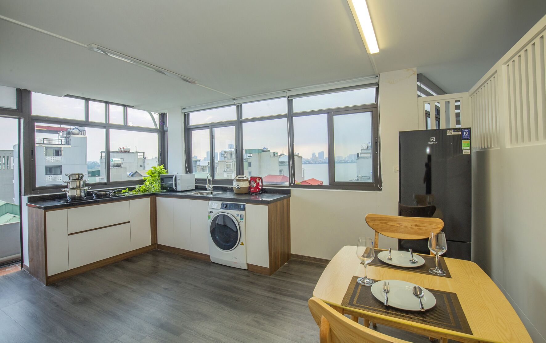 A compact kitchen with a washing machine, a microwave, and a refrigerator.