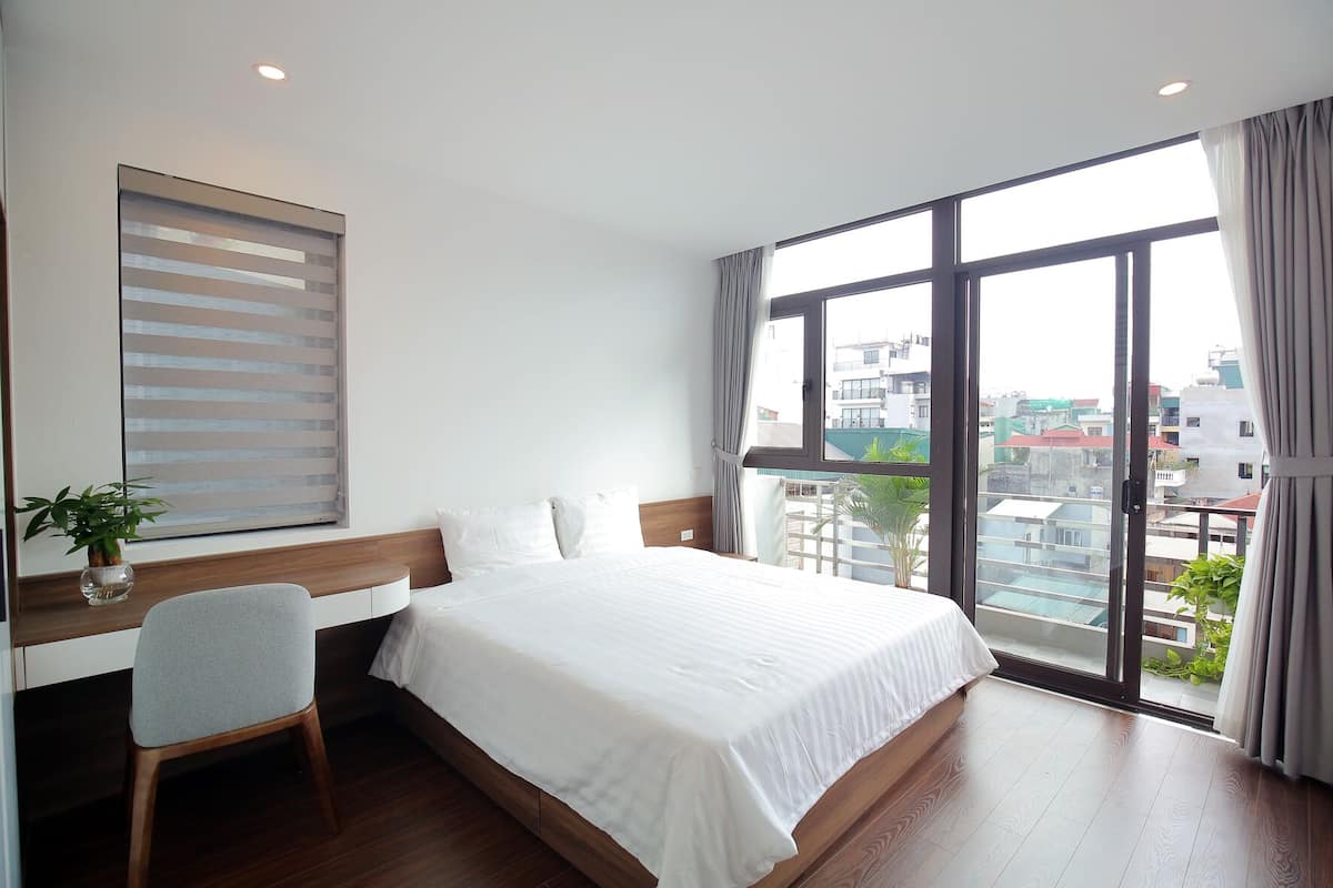 A hotel room with a large bed, a desk, and a window with a city view.