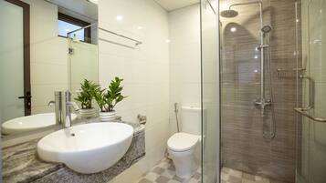 Un baño moderno con dos lavamanos, inodoro y ducha con cerramiento de vidrio.