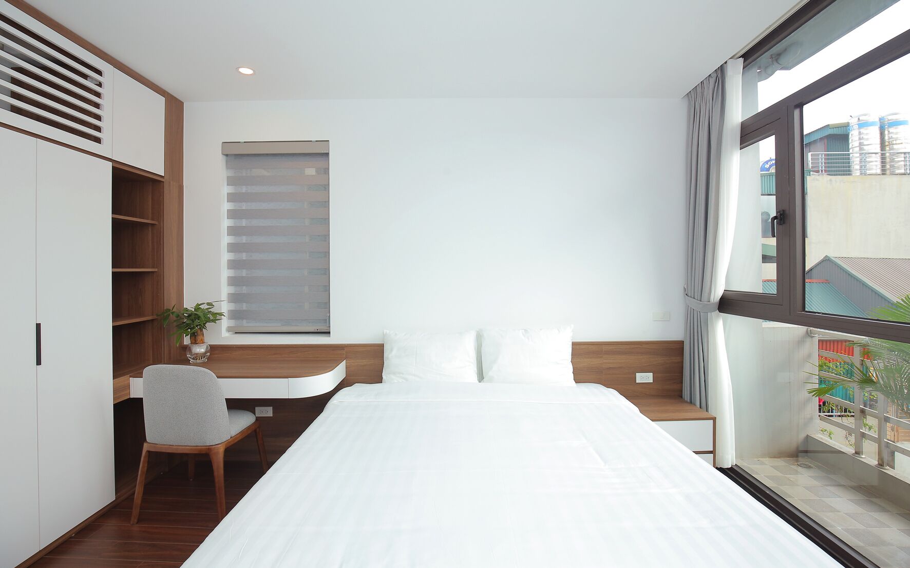 Een moderne hotelkamer met een groot bed, een bureau en een raam met uitzicht op de stad.