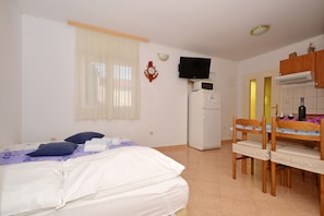 Une chambre à coucher comprenant un lit, un bureau avec une chaise, une télévision et un réfrigérateur.