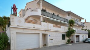 A two-story building with a garage door, a balcony with a metal railing, and a small entrance door. - STUDIO ROGULJ, 70m from the beach in Mastrinka (Mastrinka)