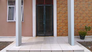 A building entrance with a double door, a window with bars, and a potted plant. - Hotel O Pondok Melati Syariah (Pekanbaru)