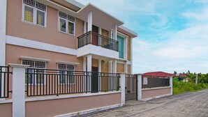 A multi-story residential building with balconies, a gated entrance, and a paved driveway. - Hotel O Pondok Melati Syariah (Pekanbaru)