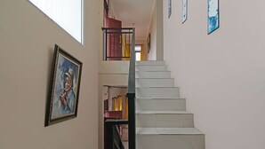 A staircase with a black railing, a painting on the wall, and a door with a red frame. - Hotel O Pondok Melati Syariah (Pekanbaru)