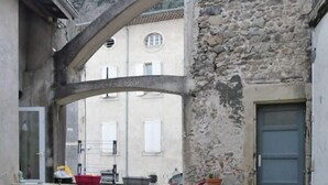 Ein schmaler Gang mit einer Steinmauer, einer kleinen Brücke und einem Tor.